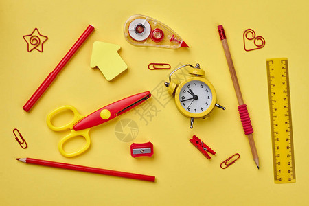 学校用品闹钟和各种黄色背景的文具物品图片