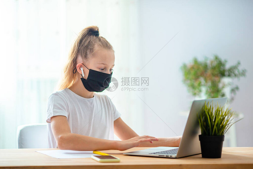 女学生戴着面具在家里用笔记本电脑做作业孩子使用小工具学习孩子们的在线教育和远程学图片