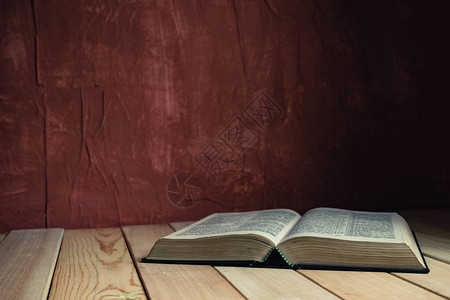在一张旧木桌上打开圣经美丽的红墙背景背景图片