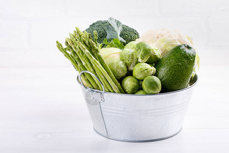 白色桌子上的分类绿色蔬菜西兰花椰菜球芽甘蓝大头菜鳄梨芦背景图片
