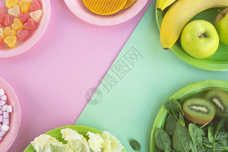 盘子上的健康和不健康的食物蔬菜水果和糖果在明亮的背景上饮食概念图片