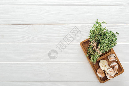 白色木制桌子上新鲜绿色胸腺和大蒜花图片