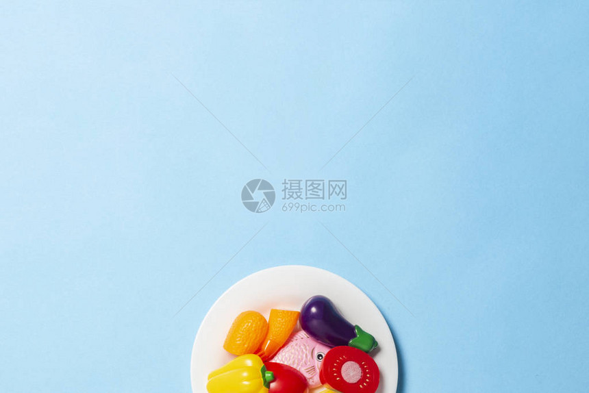 白色盘子与儿童玩具的形式在蓝色背景上的食物图片