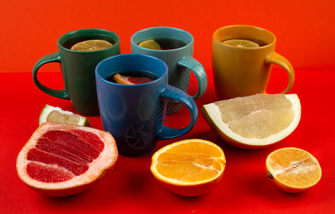 许多五颜六色的茶杯和柑橘类水果在红色背景图片