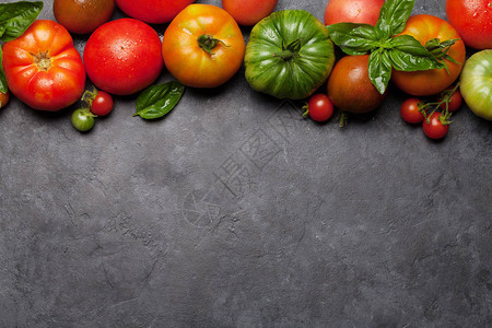 石头厨房桌上的鲜菜花色西红柿和巴西尔叶子顶端视图图片