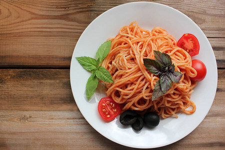 传统的意大利面食和质朴的木桌背景上的白板上的配料长意大利面配番茄酱图片