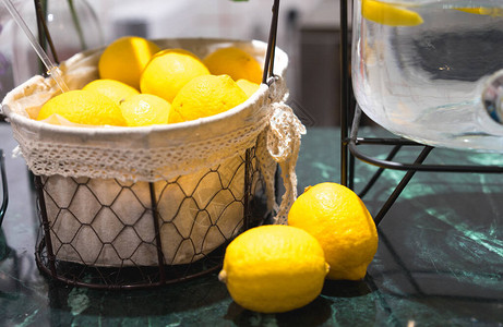 在绿大理石桌上的厨房里把两片柠檬纺织篮子和底的玻璃罐水关闭图片