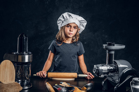 戴厨师帽的小穿笔小姑娘正在给带厨房设备的图片
