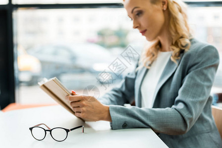 妇女阅读书旁桌上的眼镜有图片
