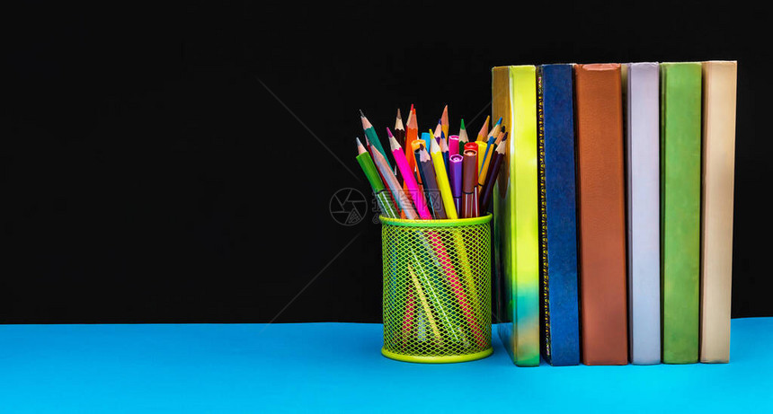 拿着彩色铅笔和一排书对着黑板文字空图片