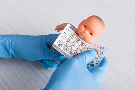 戴着乳胶手套的医生手里拿着堕胎药和婴图片