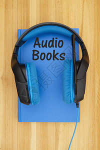 带蓝色和黑色耳头麦克风和木制桌上书本的蓝黑耳机图片