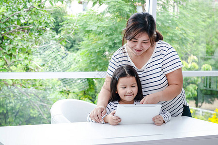 母亲在家中用平板电脑在线教授亚洲小女儿学习课程图片