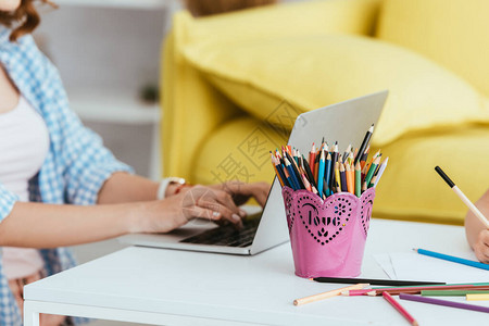 手持笔架旁边有彩色铅笔和爱情刻字的桌上笔记本电图片