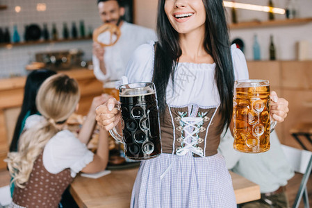 传统德国服装中女服务员持有轻啤酒和黑啤酒背景图片