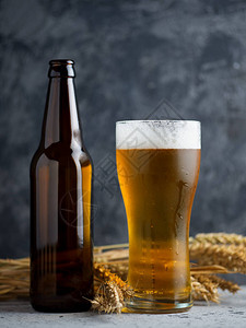 木制背景上的一杯淡啤酒和啤酒瓶图片