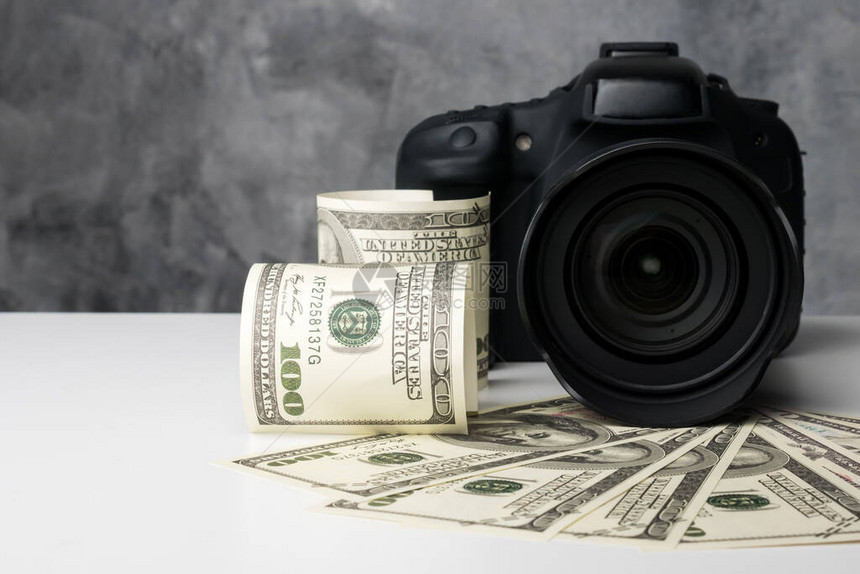 黑色数字相机和钞票在白色的桌子上图片