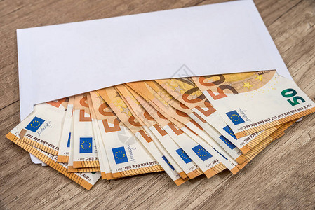 木制背景上有欧元钞票的白色信封图片