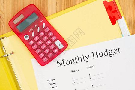 月度预算类型信息在木材桌上的黄纸盒中背景图片