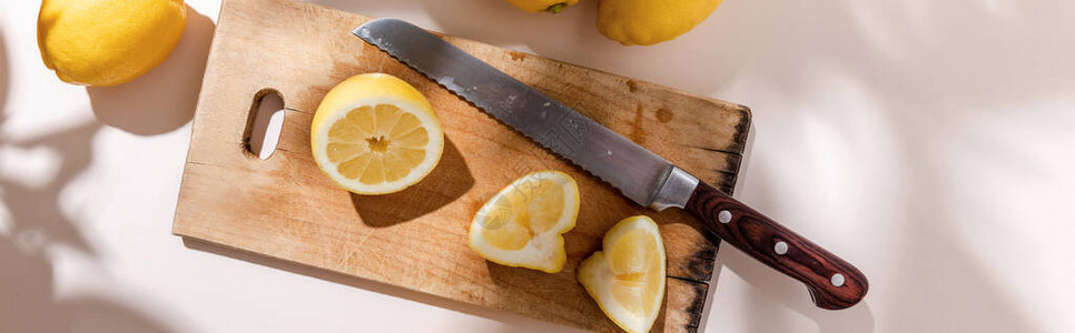 木板上切开的柠檬和灰色桌子上的刀背景图片