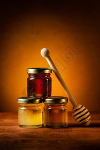 在生锈的桌子上各种类的蜂蜜放在玻璃背景图片