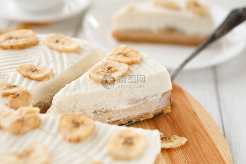 桌上有美味的香蕉蛋糕切水果饼干和焦糖以及木餐盘上的奶油淇图片