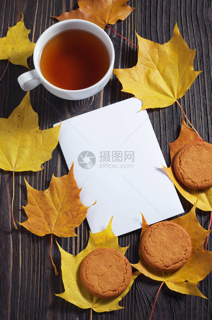 木制背景的茶杯燕麦饼干白纸和秋叶顶视图图片