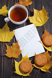 木制背景的茶杯燕麦饼干白纸和秋叶顶视图图片