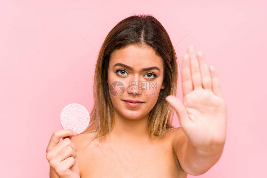 年轻caucasian女人拿着一张面部磁盘孤立地站着伸展的手显示停图片