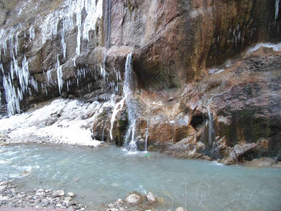 岩石上的冰冻瀑布冰柱落入河中背景图片