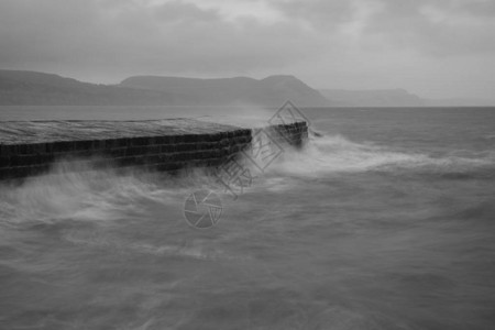 海浪在Dorset的LymeRegis码头撞上时长的暴图片