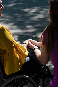 一位坐在轮椅上的母亲和她的女儿手牵图片