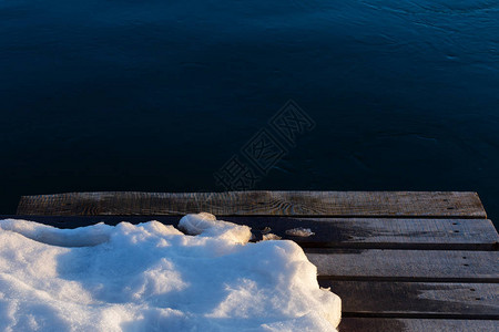 的木码头与黑水背景上的雪图片