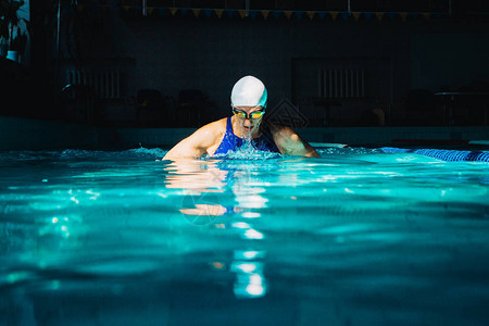 专业女子在黑暗背景上使用乳房操控技术游泳图片