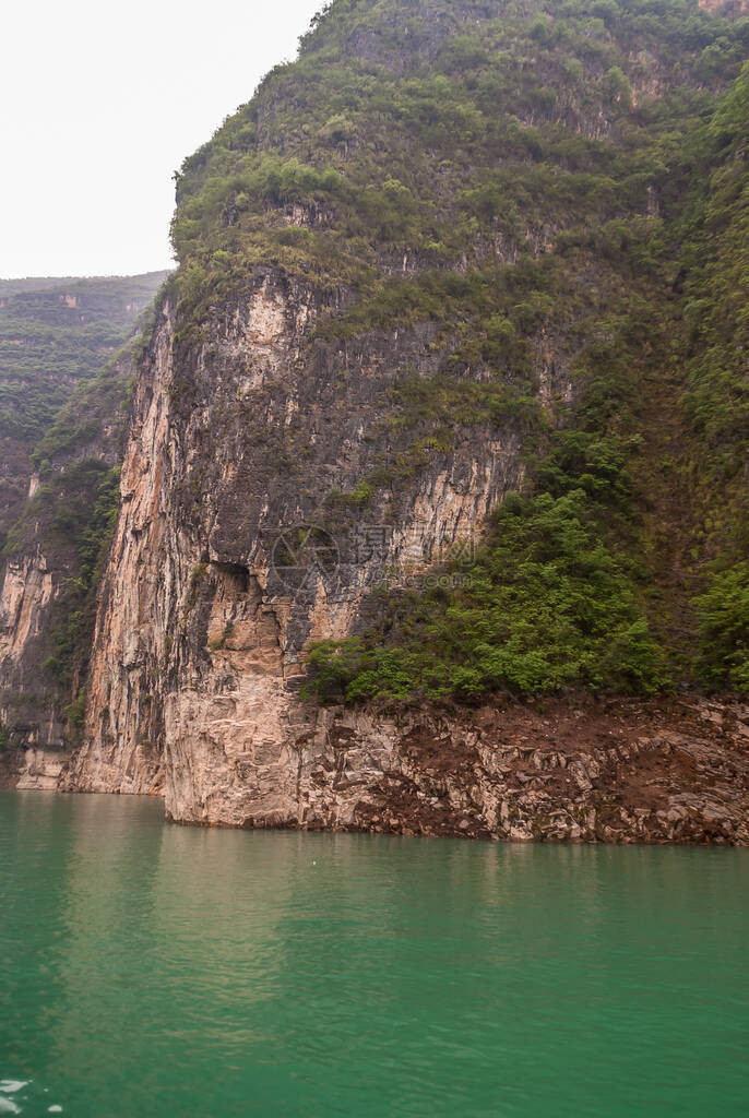 大宁河上的大雾或迷雾峡谷棕色的岩石峭壁像墙壁一样沿着峡谷下降到翡翠绿的水中一些绿色的树叶和黑图片