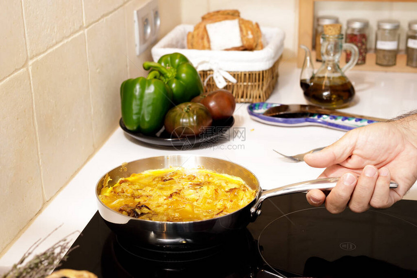 用西班牙煎蛋卷锅部分煮熟由男图片