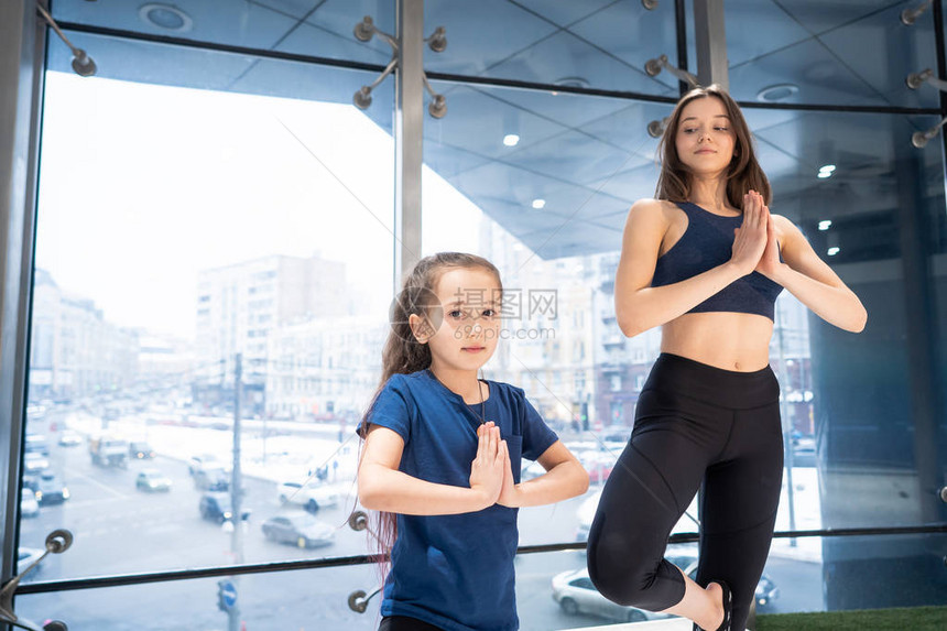 年轻成年母亲和小女儿一起在健身房练瑜伽图片