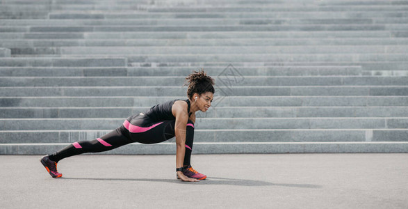 参加时装运动服装的非裔美国女孩在城市楼梯背景全景自由空间上进行锻炼图片