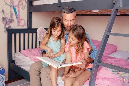 家庭教育在家上学爸在卧室里给女儿们看书家庭父亲和孩子在家共度时光父亲节假期快乐的背景图片