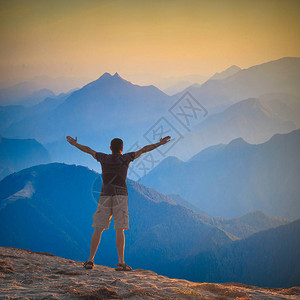 举手站在山丘上迎接山上日出的人图片
