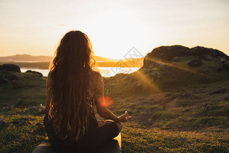 在日出山上独自冥想瑜伽的女人从后面查看旅行生活方式精神放松概念与图片