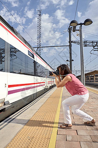 妇女拍摄火车在火车站的图片