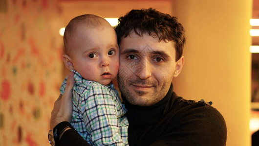 一个年轻父亲怀着一个可爱的小男孩张开眼睛的婴儿在图片