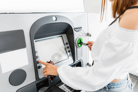 在自动取款机上使用塑料银行卡提取钱财的妇女财务和图片