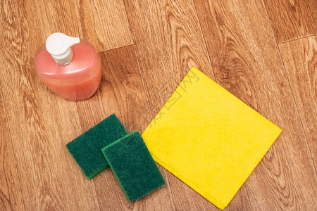 木制地板上的清洁剂海绵和黄抹布关图片