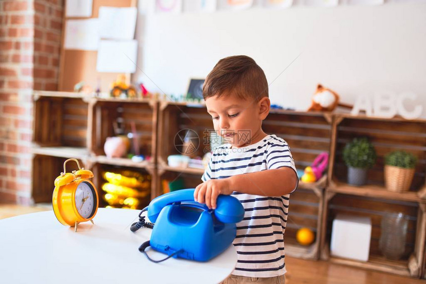 在幼儿园玩旧式蓝电话的漂亮的小孩男图片