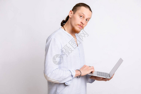一个穿着浅蓝色衬衫的人手里拿着一台笔记本电脑图片