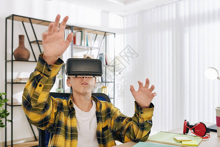 青少年男孩兴奋地在虚拟现实眼镜中测试新的游戏或教育图片