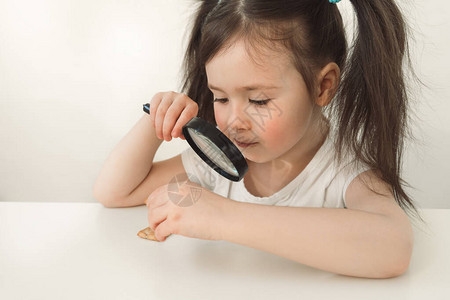 一个孩子在放大镜下检查饼干小女孩正在寻找细菌扮图片