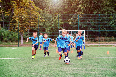 孩子们在儿童足球训练课上跑步和踢足球并图片
